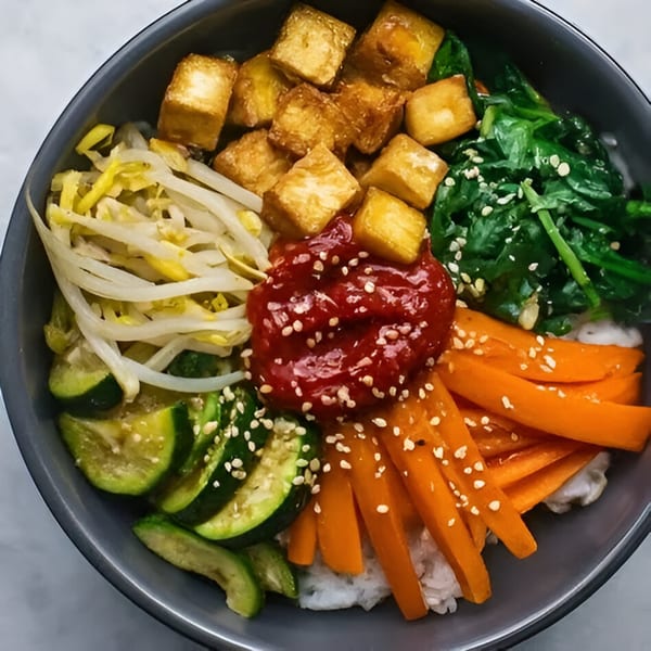 A colorful HanKki bibimbap bowl with tofu, spinach, bean sprouts, carrots, zucchini, and gochujang.