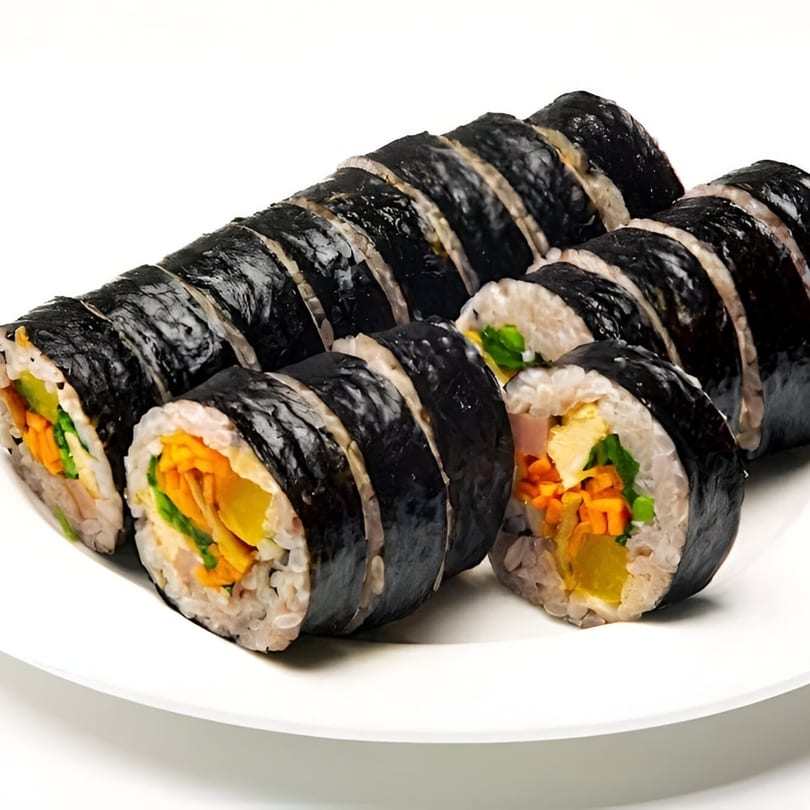 Several slices of Korean gimbap, filled with colorful vegetables and egg, arranged on a white plate.
